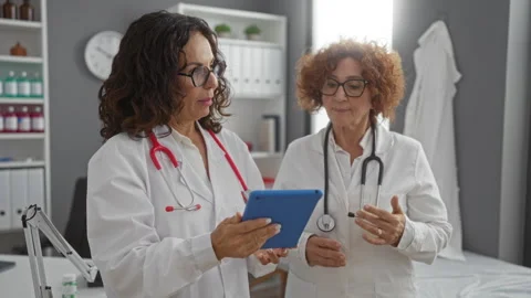 Two female doctors, middle-aged, discuss using a tablet in a hospital clini.. Stock Footage 301683309
