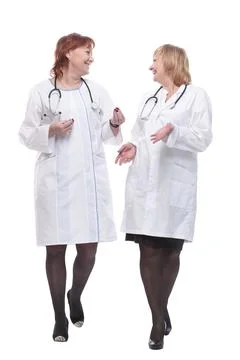 Two female doctors with stethoscopes talking as they go. Stock Photos