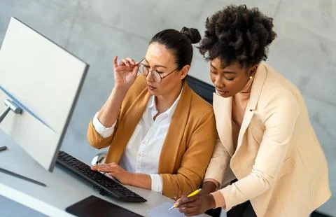 Two female entrepreneurs using computer for a productive business meeting i.. Stock Photos