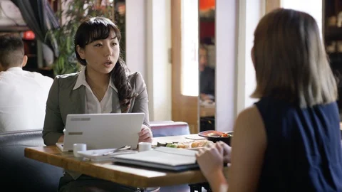Two female executives discussing over a document in restaurant Stock Footage 107987443