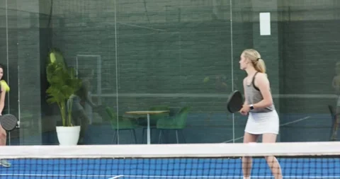 Two female friends bouncing ball with rackets to warm up, serving, volleying on Vidéo 344325094