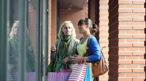 Two female friends looking at shop window Stock Footage
