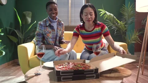 Two female friends or same sex couple celebrating with pizza and wine on moving 스톡 동영상 275240761