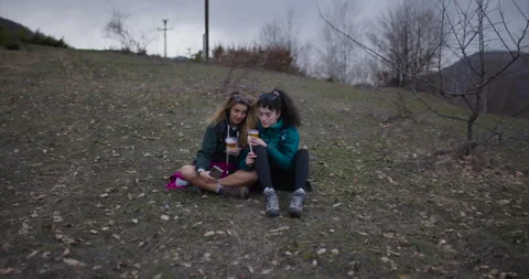 Two Female Friends Take a Break During Their Mountain Hike to Enjoy Chia Stock Footage 338359288