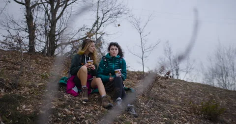 Two Female Friends Take a Break During Mountain Hike, Enjoying Drinks and Stock Footage 338361084