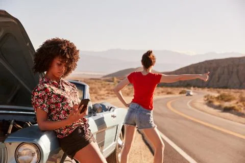 Two female friends by their broken down car at the roadside Stock Photos