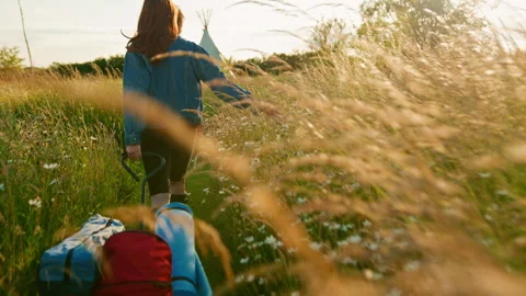 Two Female Friends Walking Pulling Trolley Through Field Towards Teepee On Stock Footage 312688505