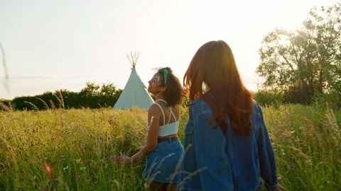 Two Female Friends Walking Pulling Trolley Through Field Towards Teepee On Stock Footage 312688693