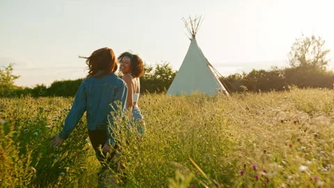 Two Female Friends Walking Pulling Trolley Through Field Towards Teepee On Stock Footage 312689413