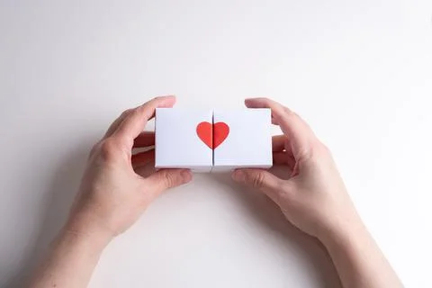 Two female hands hold two white boxes with heart on a white back Foto stock