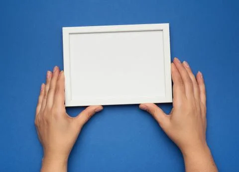 Two female hands holding a rectangular blank white frame Foto stock
