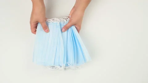 Two female hands put a stack of disposable face masks on a white table Stock Footage 137777600