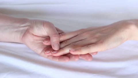 Two female hands touching each other against white sheets Stock Footage 287132192