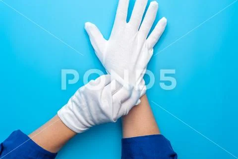 Two female hands wearing white gloves on blue background Stock Photos