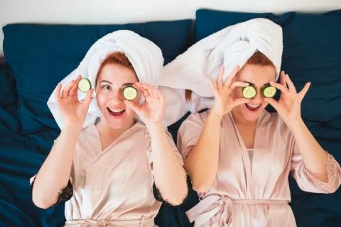 Two female models make an eye mask using fresh green cucumber. Two young women Stock Photos