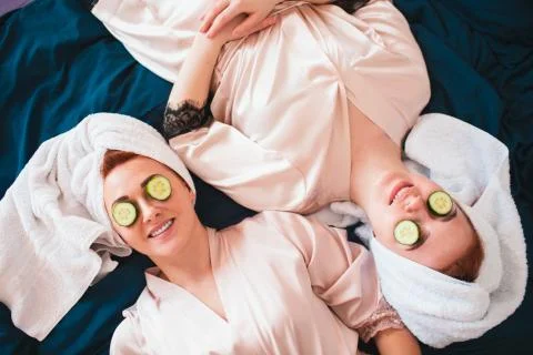 Two female models make an eye mask using fresh green cucumber. Two young women Stock Photos