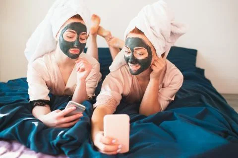 Two female models make face mask and using smartphone or phone for selfie and Stock Photos