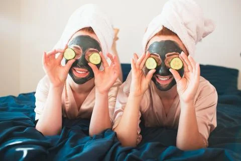 Two female models make face mask and using fresh green cucumber. Two young women Foto stock