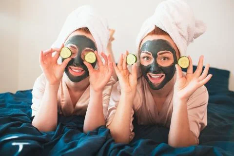 Two female models make face mask and using fresh green cucumber. Two young women Stock Photos