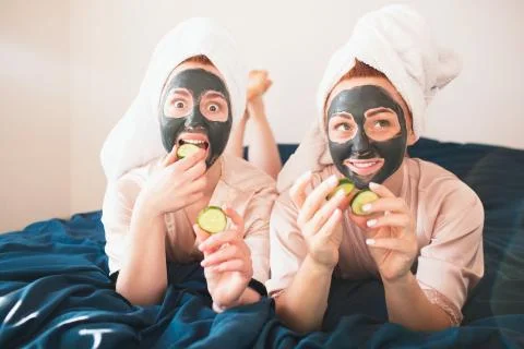 Two female models make face mask and using fresh green cucumber. Two young women Stock Photos