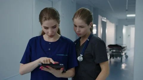 Two female nurses are standing in the hospital corridor with a tablet Stock Footage 230238084