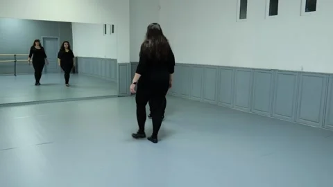 Two female plus size models in black clothes are dancing in the hall. Slow motio Stock Footage 244840309