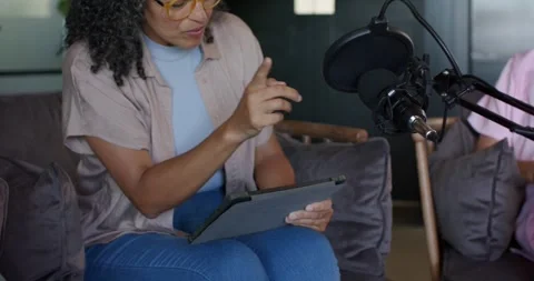 Two female podcasters on couch in studio adjusting mic after pop filter shift, Stock Footage 341665484