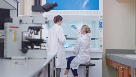 Two female scientists analyzing samples in a laboratory fume hood 스톡 동영상 346939536