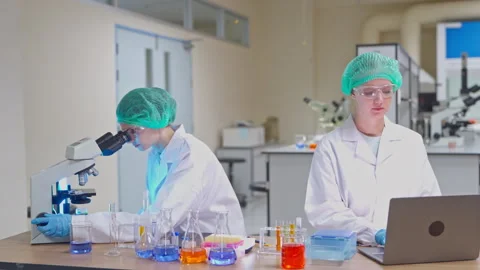 Two female scientists using a microscope and laptop in a laboratory Video stock 346938658