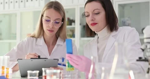 Two female scientists working in a laboratory with yellow liquid tester Vidéo 282250836