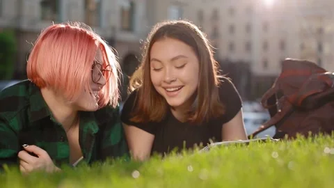 Two female student on the grass with a book Stock Footage 134894973