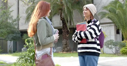 Two female students approaching on campus holding notebooks and folders sparking Stock Footage 343098106