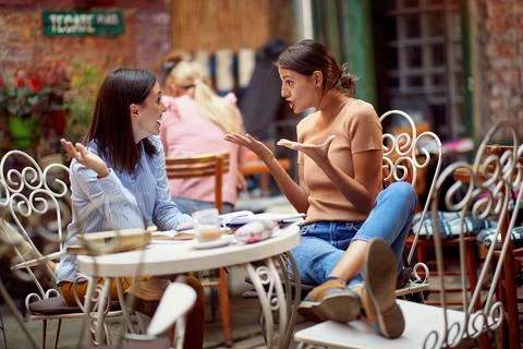 Two female students having an interesting conversation while have a drink in  Stock Photos