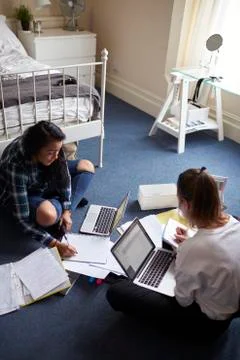 Two Female Students With Laptops Studying In Bedroom Stock Photos