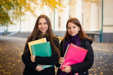Two female students with learning materials near university building Stock Photos