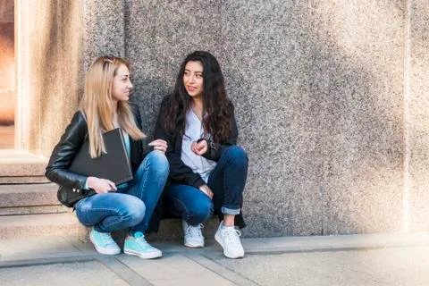 Two female students talking by the wall Stock Photos