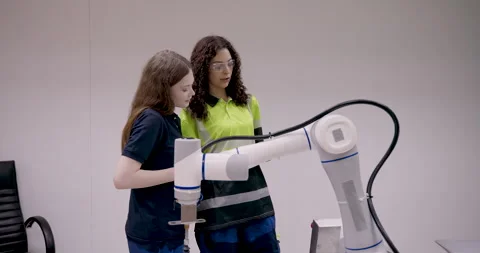 Two female technicians collaborating in robotics lab by demonstrating robotic Stock Footage 313648993