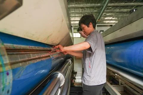 Two Female Workers Cooperating to Mount Printing Film on Printing Machine Stock Photos