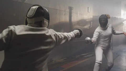 Two fencers duel in a dark and dingy fencing gym in slow motion 스톡 동영상 107755430
