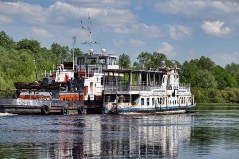 Two ferries move on the river under a bright sky with clouds. Trees line the  Fotos de archivo