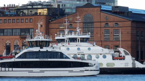 Two ferries, one of them electric boat Kongen, cruising past the waterfront Stock Footage 232258049