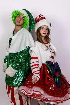 Two festive models are posing back-to-back in colorful Christmas-themed outfits Stock Photos