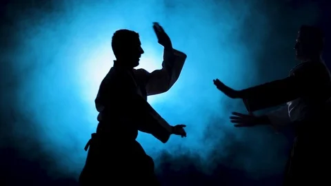 Two fighters Practicing aikido technique, silhouettes of masters in dark studio Stock Footage 126352320