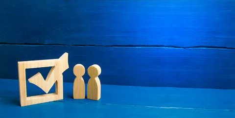 Two figures stand together next to tick in the box. The concept of election.. Stock Photos