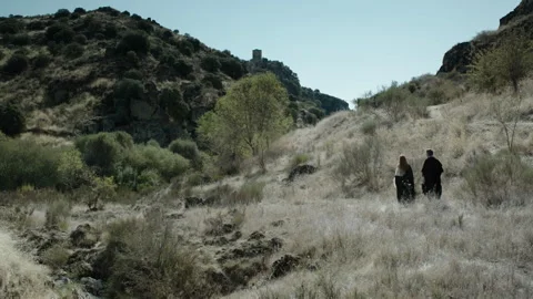Two figures walk through a dry landscape on a sunny day in nature Stock Footage 327941702