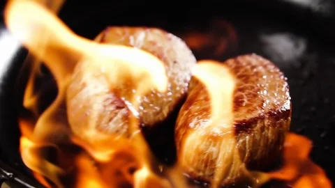 Two filet mignon steaks fall into a pan with flame, slow motion. Stock Footage 126220815