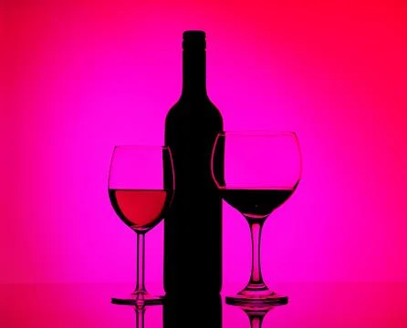 Two filled glasses with red wine and sherry, black silhouette of bottle Stock Photos