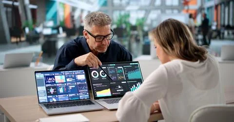 Two Finance Analysts Review Data On Laptop, Discussing Business Performance T Stock Photos
