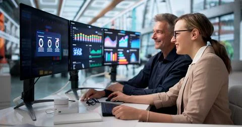 Two Finance Analysts Sharing A Joyful Moment While Reviewing Data Together. Stock Photos