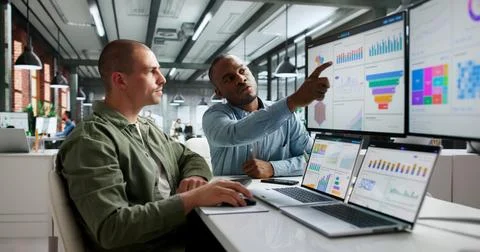 Two Financial Analysts Are Looking At Dashboards On Computers During Market R Fotos Stock